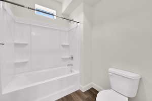 Bathroom with shower / bathtub combination and dark wood-style floors