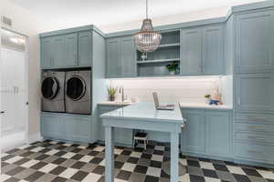 Laundry area featuring visible vents, cabinet space, a chandelier, dark floors, and washer and dryer
