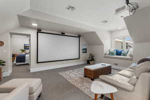 Home theater with visible vents, baseboards, carpet floors, and lofted ceiling