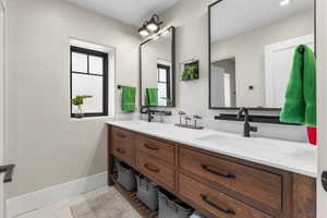 Bathroom with a sink, baseboards, tile patterned floors, and double vanity