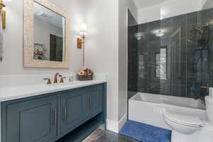 Full bath featuring vanity, marble finish floor, toilet, and tub / shower combination