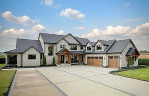 Modern farmhouse style home featuring a garage, roof with shingles, driveway, and a front yard