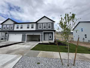 View of front of property with fence, driveway, a garage, a front lawn, and board and batten siding