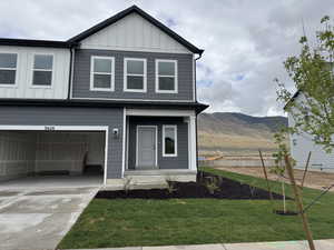 View of front of home featuring board and batten siding, driveway, a mountain view, an attached garage, and a front yard