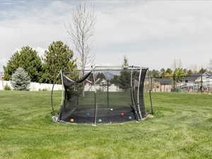View of yard with a trampoline and fence