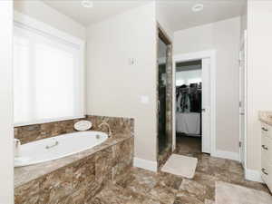 Main Bathroom with a Jetted Therapy bathtub, a steam shower, vanity, baseboards, and a spacious closet