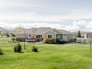 Back of house featuring a lawn, a mountain view, fence, and a patio
