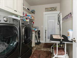 Clothes washing area featuring baseboards, cabinet space, and washing machine and clothes dryer