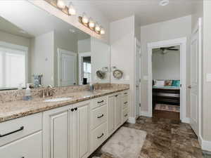 Full bath featuring double vanity, a sink, ensuite bath, and a wealth of natural light