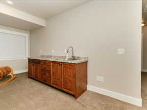 Bar featuring a sink, baseboards, recessed lighting, and light colored carpet