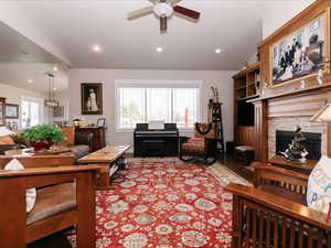 Living room featuring recessed lighting, a ceiling fan, vaulted ceiling, and a fireplace