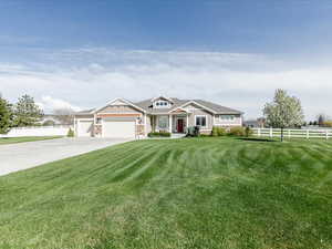 View of front of property with an attached garage, board and batten siding, fence, and a front yard