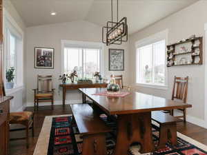 Dining area featuring baseboards, a notable chandelier, dark wood finished floors, and lofted ceiling