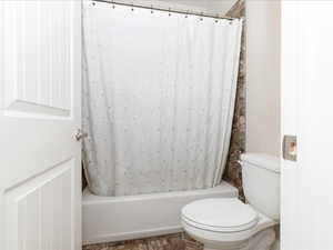 Full bath featuring shower / bathtub combination with curtain and toilet