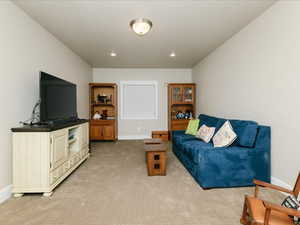 Living room featuring baseboards, recessed lighting, and light carpet