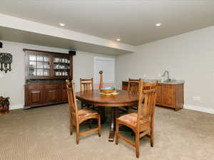 Dining room featuring indoor wet bar, recessed lighting, baseboards, and light colored carpet
