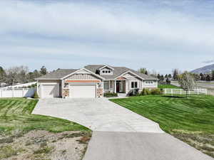 Craftsman-style home featuring fence, an attached garage, a front lawn, board and batten siding, and driveway