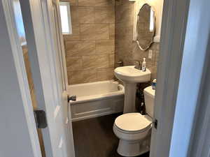 Full bath featuring shower / bathtub combination, toilet, and tile walls