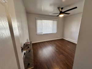 Empty room featuring visible vents, a ceiling fan, baseboards, and dark wood-type flooring