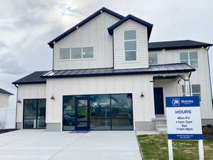 View of front facade featuring a front porch, 3 car garage, board and batten siding, a standing seam roof, and metal roof