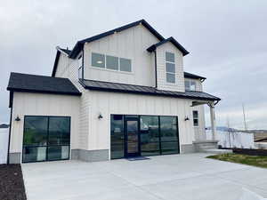 Front view of house featuring a 3 car garage, metal roof, a standing seam roof, and board and batten siding