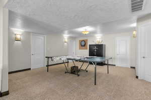 Game room with carpet floors, baseboards, a textured ceiling, and visible vents