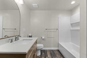 Full bath with baseboards, vanity, toilet, and wood finished floors