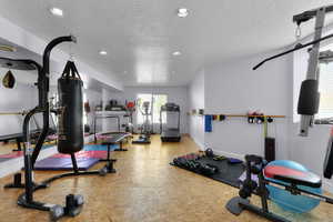 Exercise area with recessed lighting, a textured ceiling, and baseboards