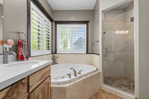 Full bathroom featuring a jetted tub, wood finished floors, vanity, and a shower stall
