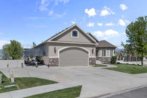 View of front of home featuring fence, an attached garage, stone siding, stucco siding, and a front yard