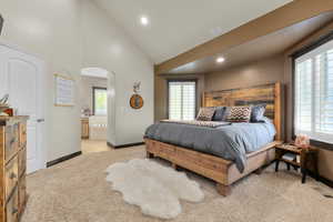 Bedroom with connected bathroom, light carpet, arched walkways, recessed lighting, and baseboards