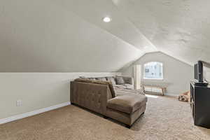 Interior space featuring carpet floors, baseboards, recessed lighting, and lofted ceiling