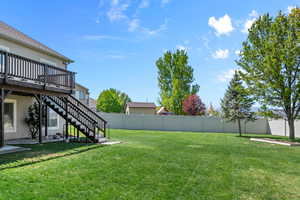 View of yard with a fenced backyard, a wooden deck, and stairway