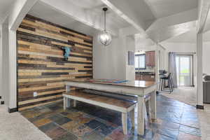 Dining space featuring stone tile floors, a notable chandelier, and wooden walls
