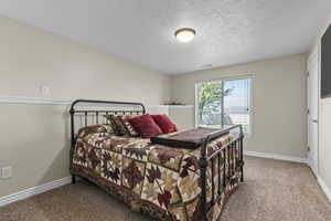 Carpeted bedroom featuring a textured ceiling, baseboards, and visible vents