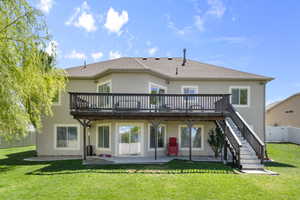 Rear view of house with stucco siding, a deck, a fenced backyard, a patio area, and a lawn