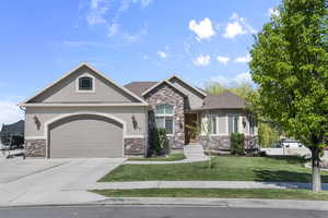 Craftsman inspired home with a front lawn, concrete driveway, an attached garage, stone siding, and stucco siding