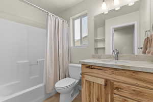 Full bath featuring vanity, shower / bath combo, toilet, and wood finished floors