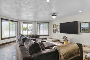 Living area featuring recessed lighting, a textured ceiling, dark wood finished floors, and baseboards