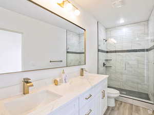 Bathroom featuring double vanity, a sink, toilet, and a shower stall