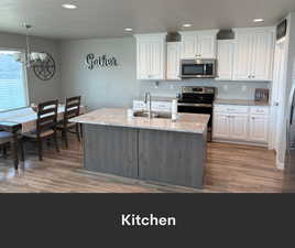 Kitchen featuring stainless steel appliances, a chandelier, wood finished floors, recessed lighting, and a sink