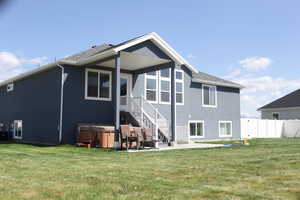 Rear view of property featuring a hot tub, a patio, and stucco siding