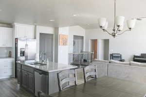 Kitchen featuring appliances with stainless steel finishes, a sink, white cabinetry, dark wood finished floors, and a breakfast bar