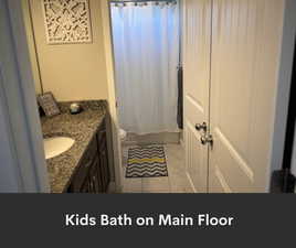 Bathroom with vanity, toilet, tile patterned flooring, and shower / bath combination with curtain