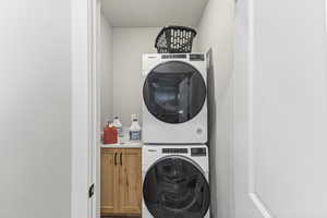 Laundry area featuring cabinet space and stacked washer and clothes dryer