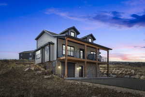 Exterior space featuring board and batten siding, an attached garage, a balcony, and stone siding