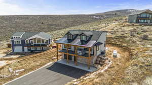 Exterior space featuring a garage, aphalt driveway, a balcony, and stone siding