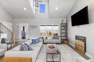 Living room featuring stairs, high vaulted ceiling, baseboards, and wood finished floors