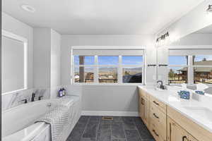 Bathroom with a sink, double vanity, baseboards, visible vents, and a bath