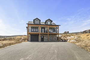 Beach home with board and batten siding, an attached garage, driveway, and a balcony